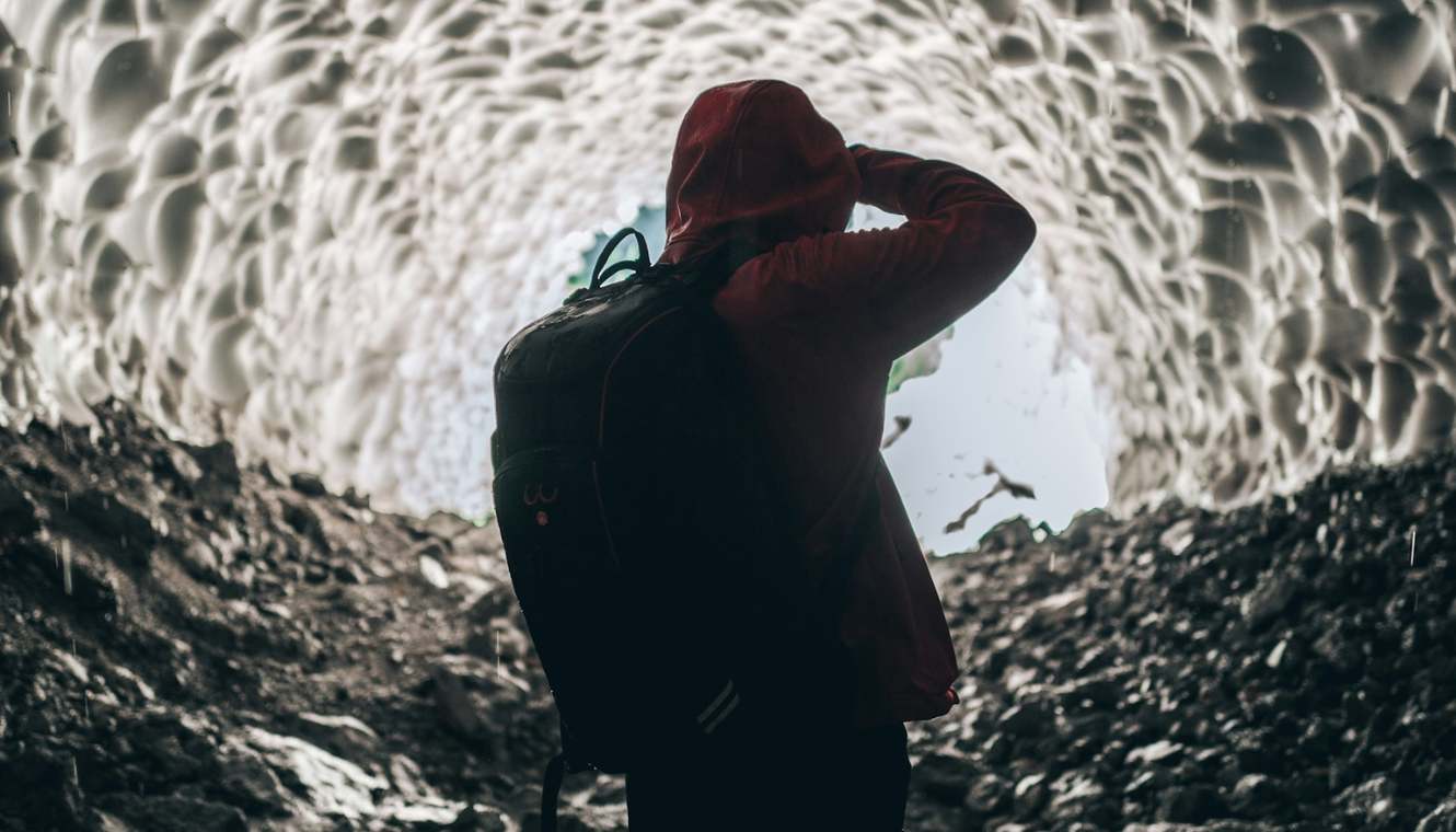 Un aventurero observando una caverna de hielo, ilustrando un momento de descubrimiento y exploración, potencialmente como metáfora del proceso de diseño y la búsqueda de soluciones innovadoras.